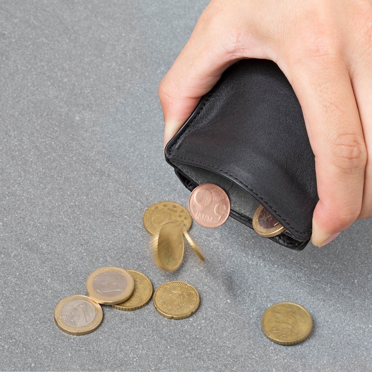 hands pinching flexlock coin pocket on a black wallet to remove coins