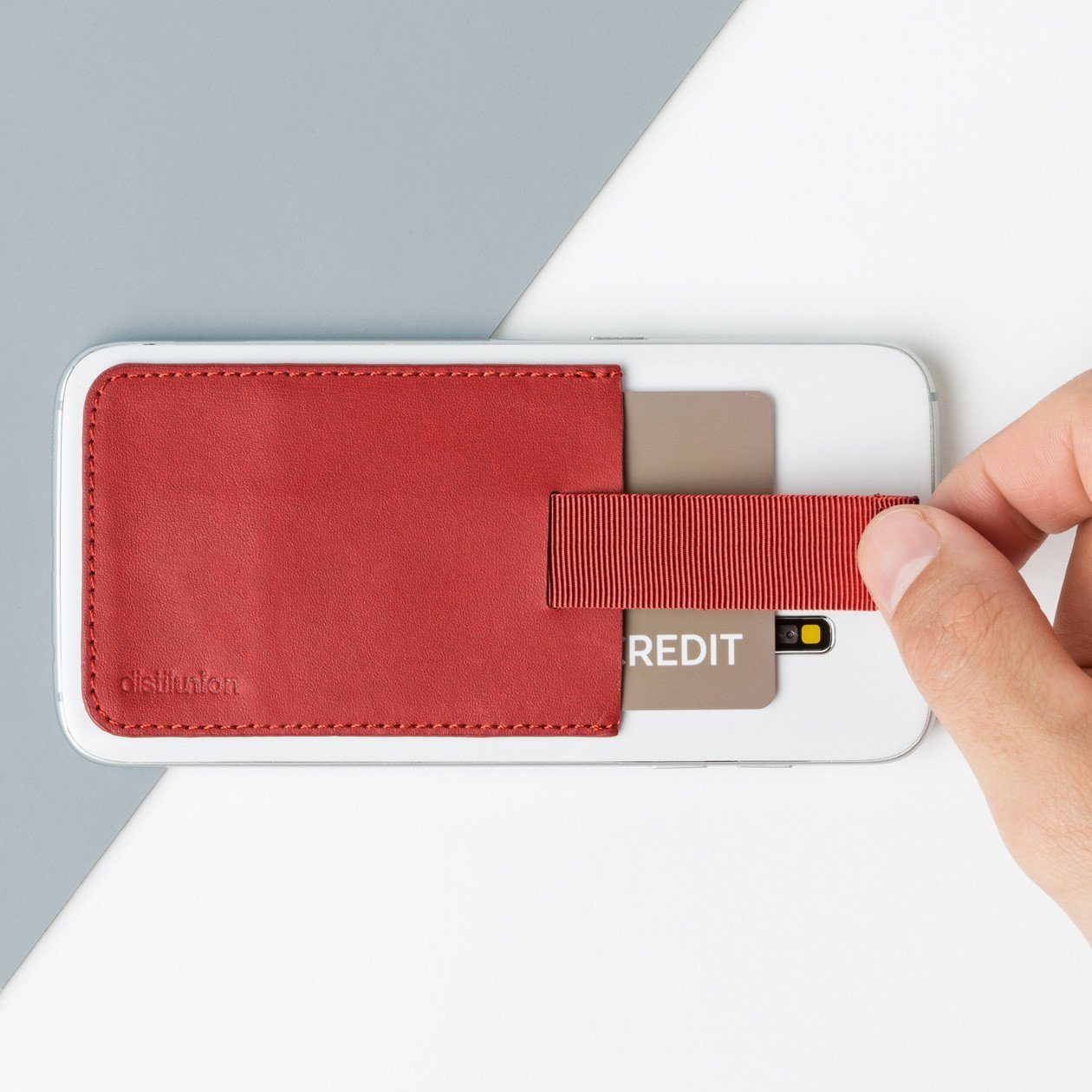 red leather wally junior stick-on attached to an iphone with hand using pull-tab to withdraw cards