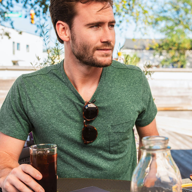 bearded man with distil cooper sunglasses hanging from green tshirt collar