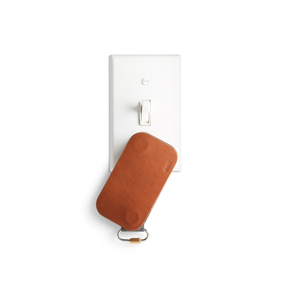 distil brown leather keyfolio hanging from white light switch plate with magnets