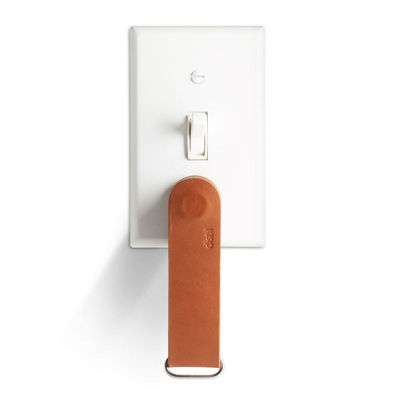 distil brown leather keyloop cover hanging from white light switch plate with magnets