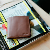 closed Distil Agent slim billfold wallet in hickory leather sits on a magazine