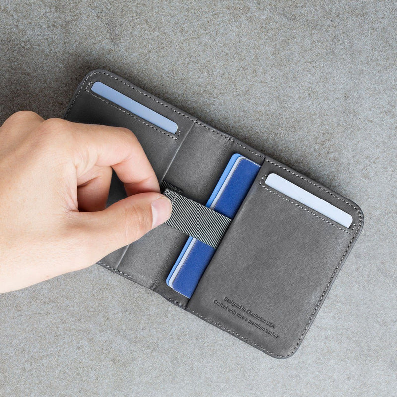 left hand using the pull-tab to take out cards from the slate colored slim billfold wallet